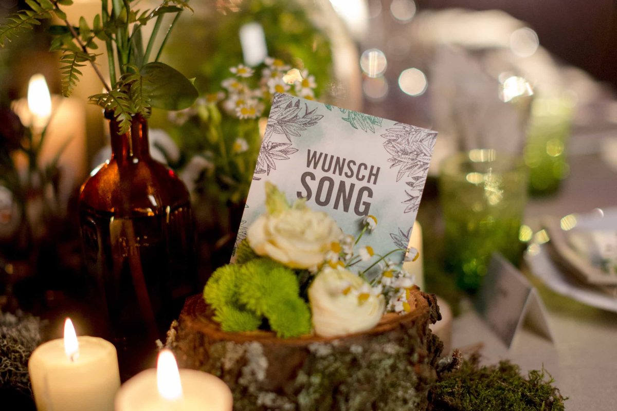 Karte mit der Aufschrift Wunsch Song, die in einem Blumenarrangement steckt