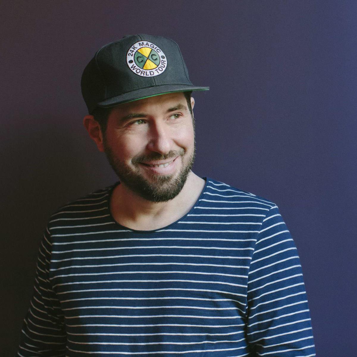 Portrait von Lounge DJ Markus Rosenbaum mit Kappe und gestreiftem Shirt