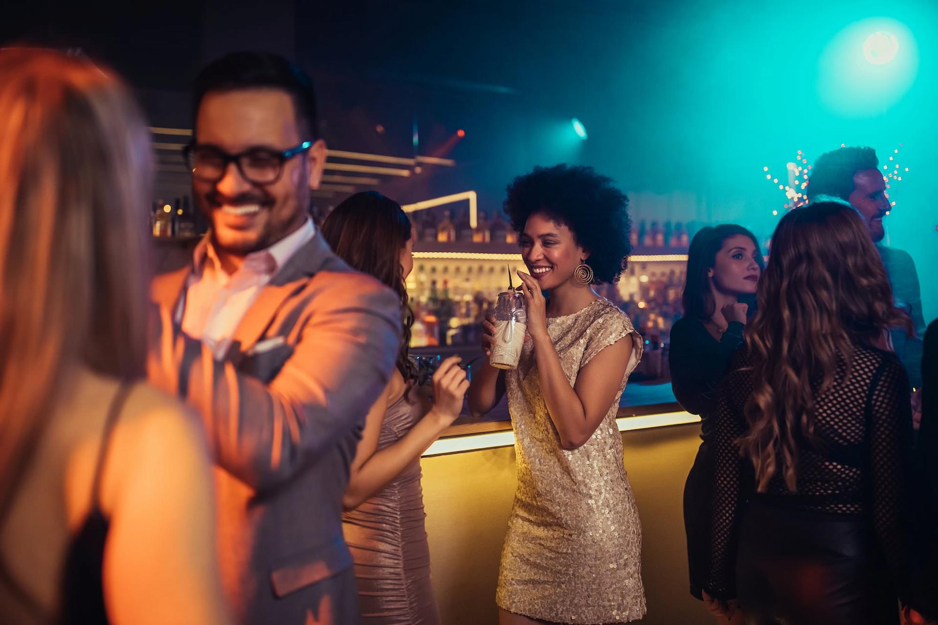 Party Gäste unterhalten sich bei der Bar und nehmen Drinks zu sich