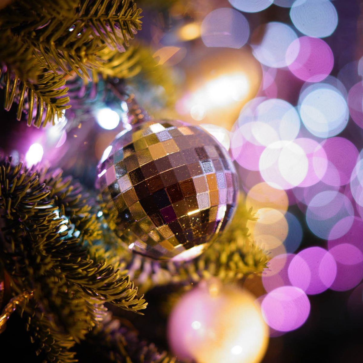 A small disco ball hangs as decoration on a Christmas tree.